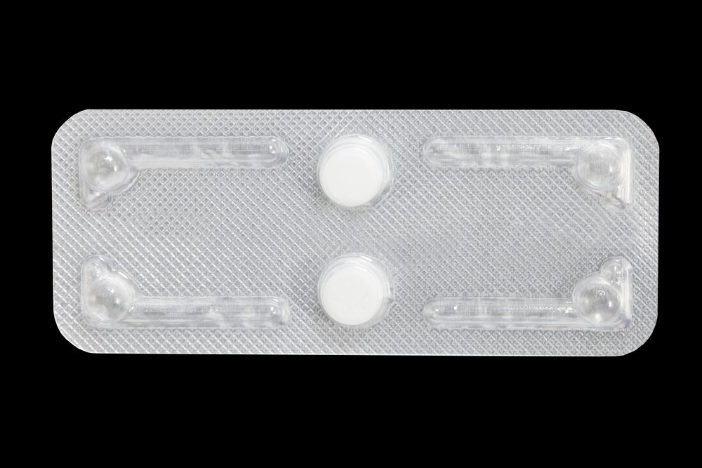 [PHOTO: Two white pills in foil blister pack, against black background.]