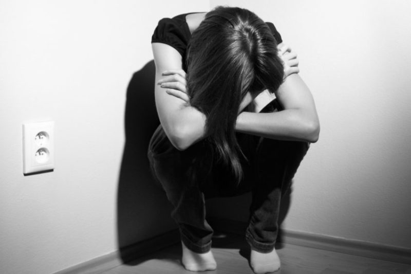 black and white photo of sad woman in corner