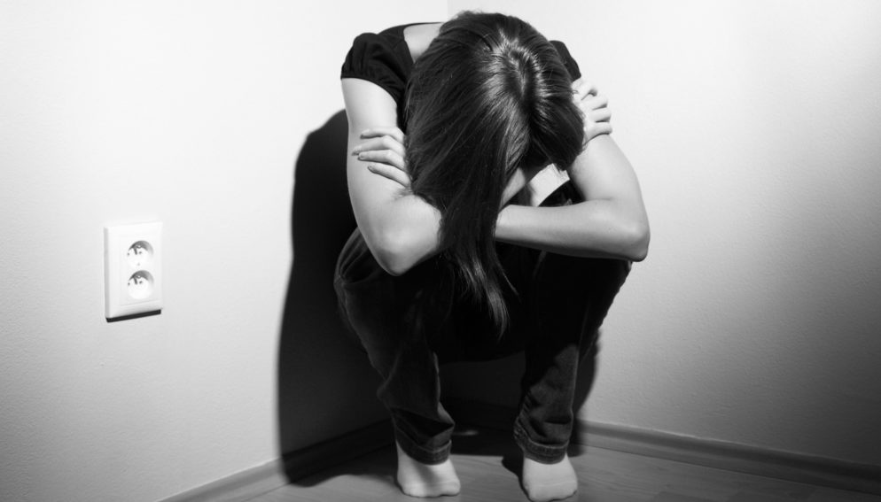 black and white photo of sad woman in corner