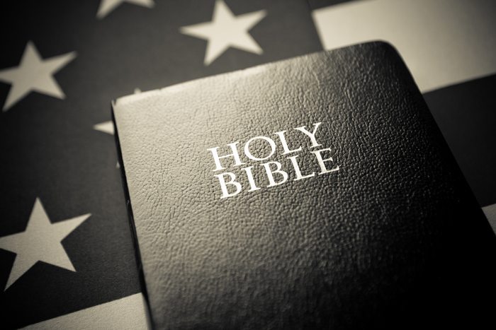 Photo of a bible in front to a U.S. flag