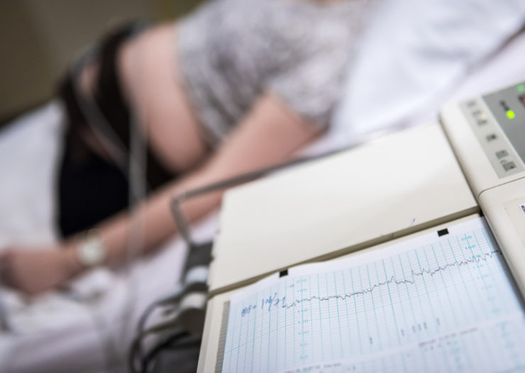 Photo of person laying in hospital bed hooked up to monitors