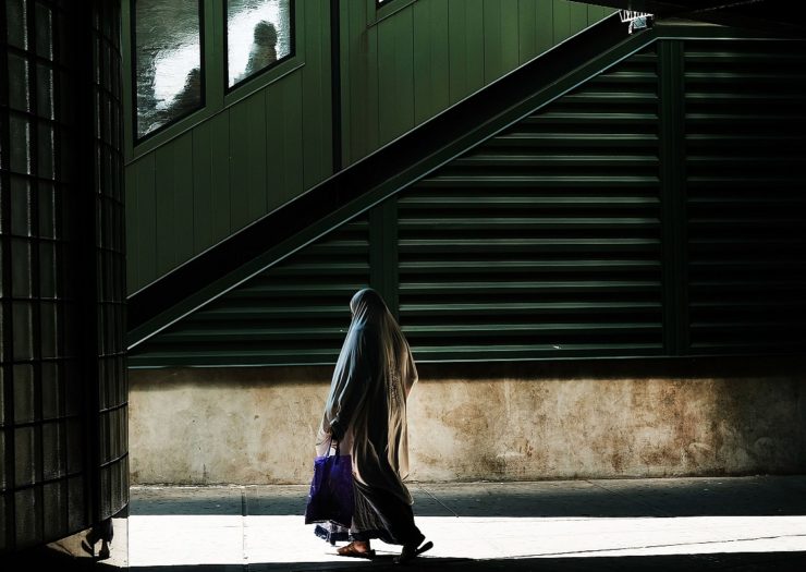 [Photo: A Muslim woman walks in a neighborhood.]
