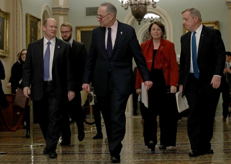 [Photo: Senate Minority Leader Chuck Schumer walks with Sen. Chris Coons (D-DE), and other Democratic senators.]