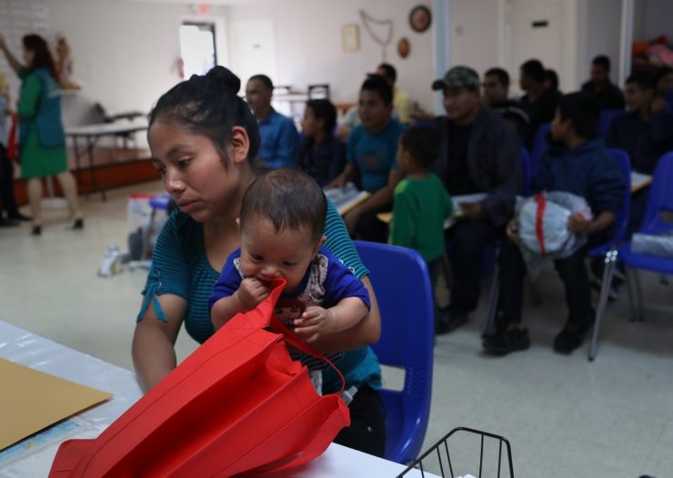 [Photo: A mother holds her child Immigrant Respite Center.]