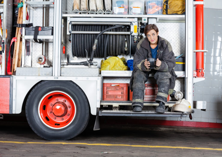 [Photo: A female firefighter sits on a fire truck.]
