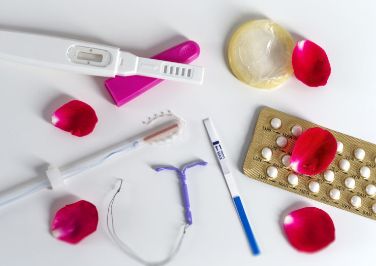 [photo: Various forms of contraception spread out on a white background.]