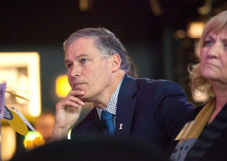 [Photo: Gov. Jay Inslee sits forward while listening to a speaker at an event.]