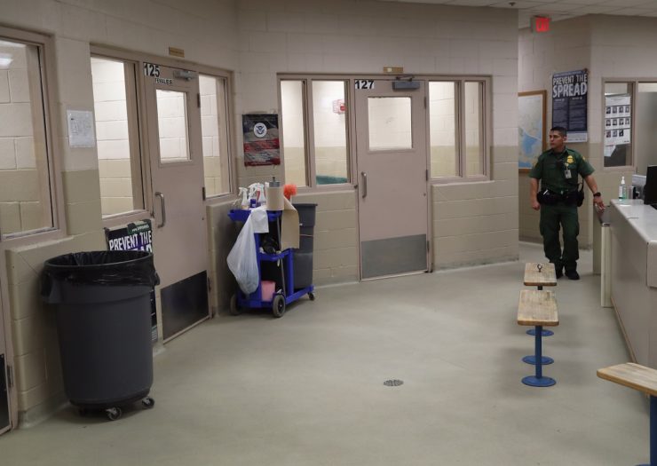 [Photo: A border patrol agent walks around a detention center]