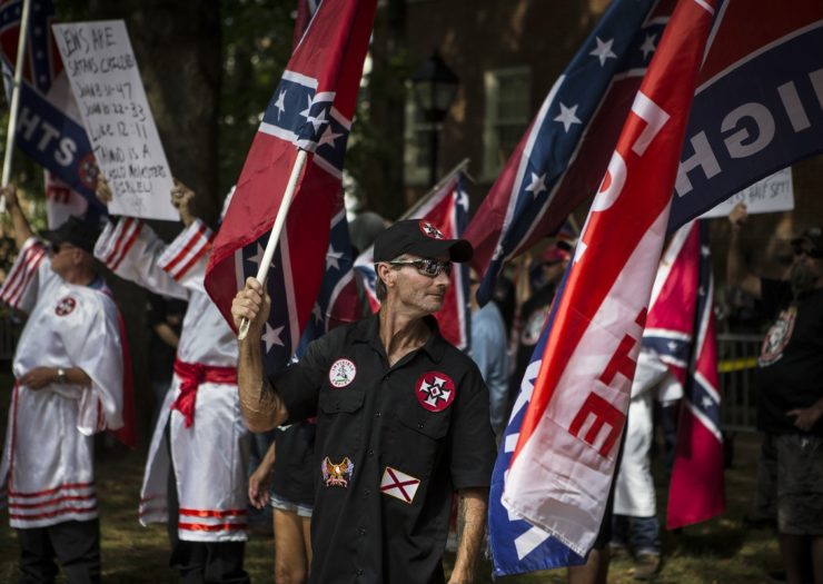 [Photo: Ku Klux Klan members protest with flags near a statue of General Robert E. Lee]