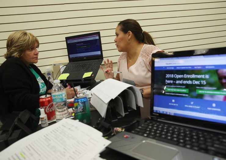 [Photo: An insurance agent speaks with a woman about signing up for health care.]