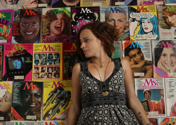 [Photo: A woman sits on a large pile of Ms. magazines.]
