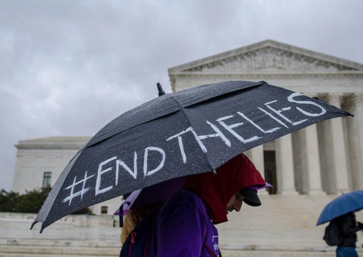 [Photo: An activist carries an umbrella with the hashtag 