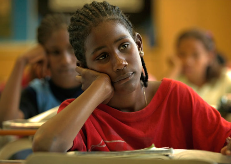 [Photo: A Black student in class leans on their hand while in class]