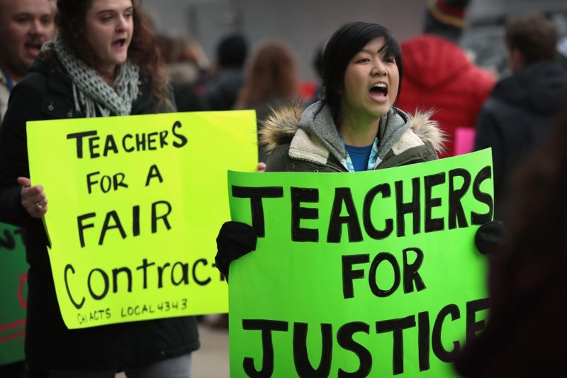 [Photo: Teaches march with signs that read
