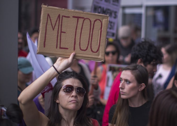 [Photo: A woman holds a sign that reads 