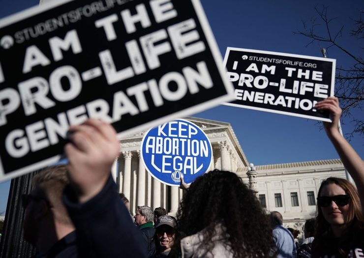 [Photo: Anti-Choice activists try to block the sign of a pro-choice activist outside of the Supreme Court]
