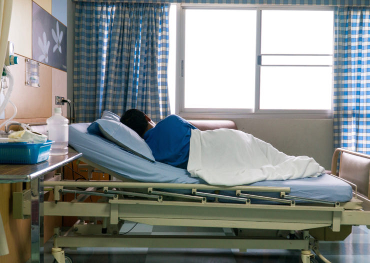 [Photo: A patient lies in a hospital bed]