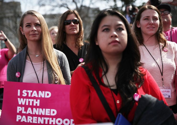 [Photo: A group of women gather to listen to a speaker during a Planned Parenthood rally.]