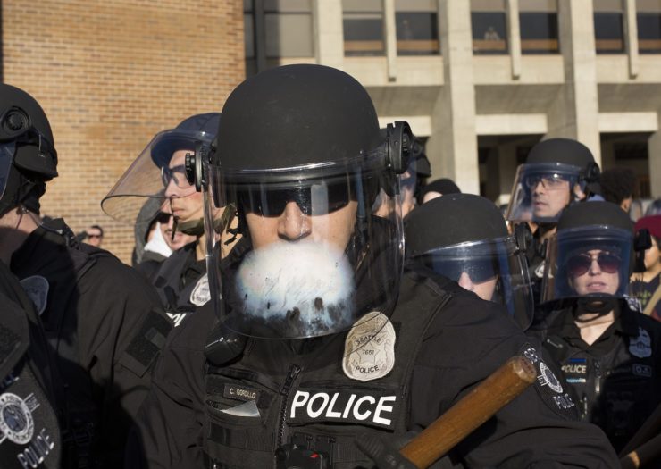 [Photo: A group of cops with masks gather near a counter-protest]