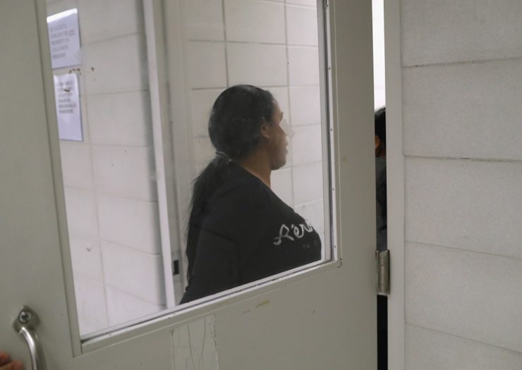 [Photo: A woman detained by ICE enters a cell]