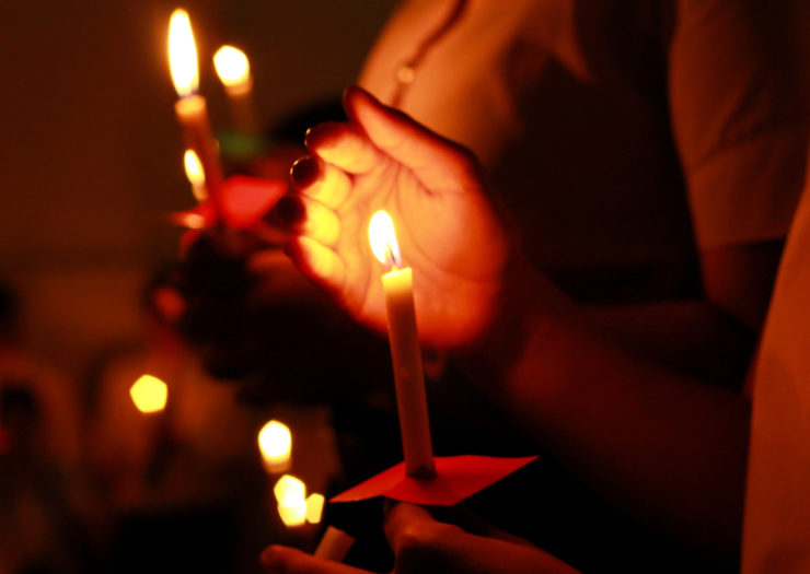 [Photo: Stock image of a candlelight vigil.]