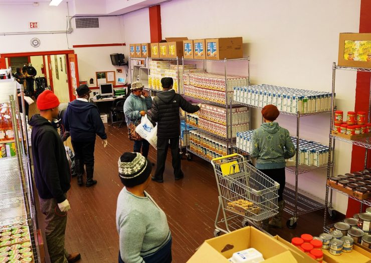 [Photo: People collect food at a food pantry]
