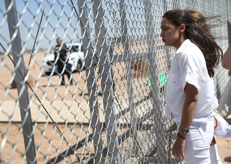 [photo: Alexandria Ocasio-Cortez stands at the U.S.-Mexico border]