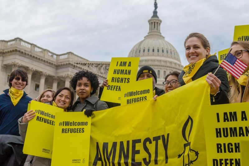 [Photo: Activists holds signs that read