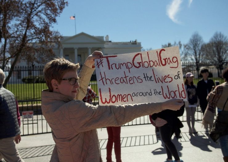 [Photo: Outside of the White House, an activist holds a sign that reads 