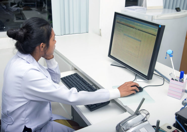 [Photo: A doctor looks over medical records on the computer]