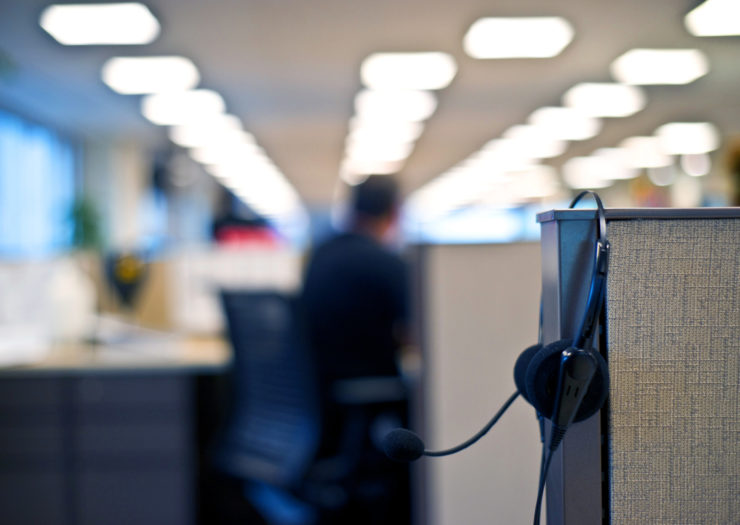 [Photo: A headset sits on a shelf at a call center]