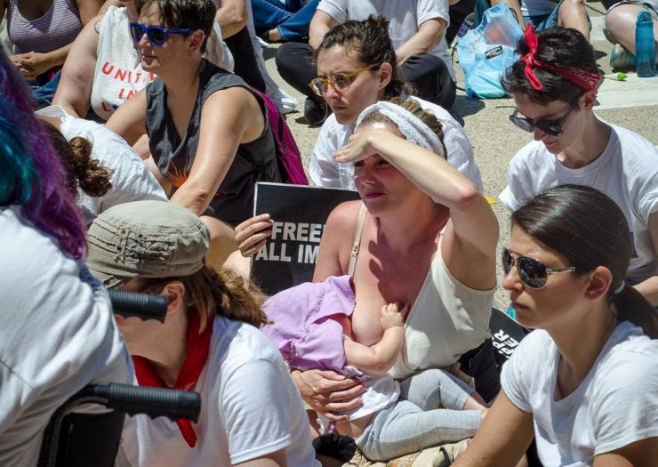 [Photo: A woman breastfeeds at a protest]