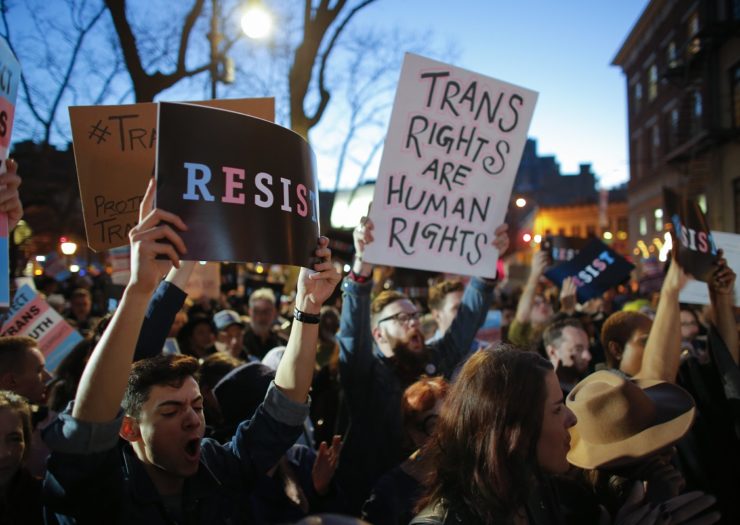 [Photo: A group of people rally outside in support of transgender rights]