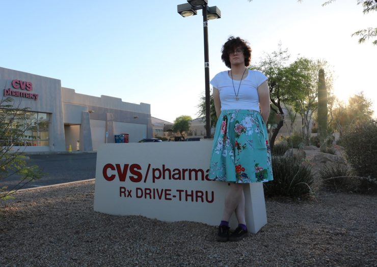 [Photo: A transgender woman stands near a CVS/pharmacy sign]
