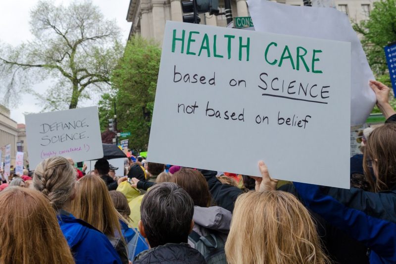 [Photo: A protester holds a sign that reads
