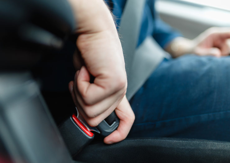 [Photo: A woman fastens a seatbelt in a car]