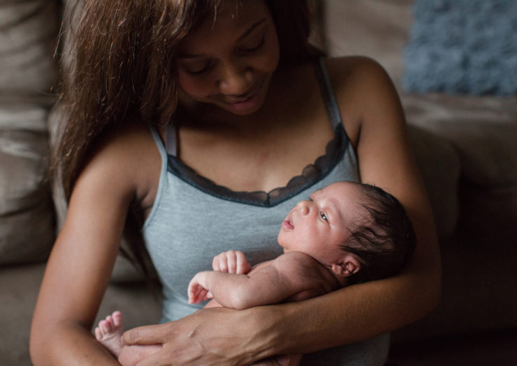 [Photo: A Black mother holds her infant]