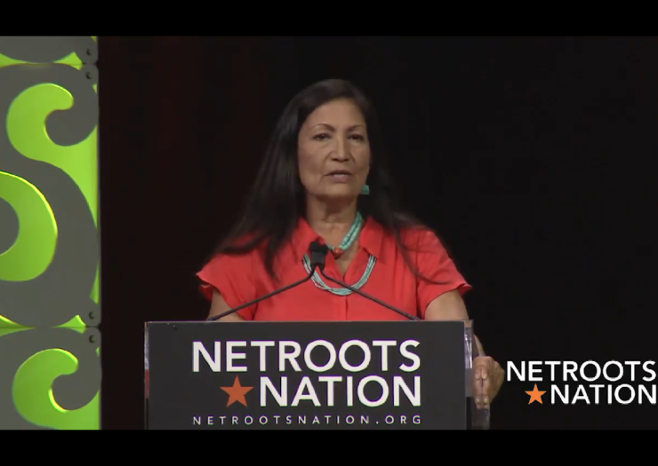 [Photo: Deb Halland speaks during the 2018 Netroots Nation conference]