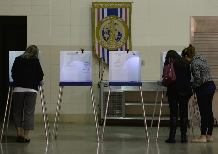 [Photo: People vote at a voting booth]