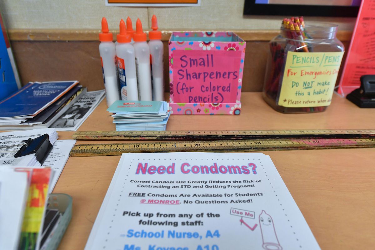 [PHOTO: Common school supplies such as pencils and rulers on a desk with a flier telling students about free condoms available from a school nurse.]