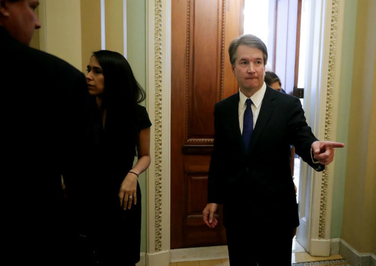 [Photo: Judge Brett Kavanaugh points at someone outside of the frame as he enters a room]