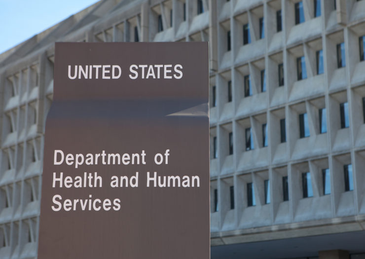[Photo: U.S. Department of Health and Human Services building with sign of its name in front.]