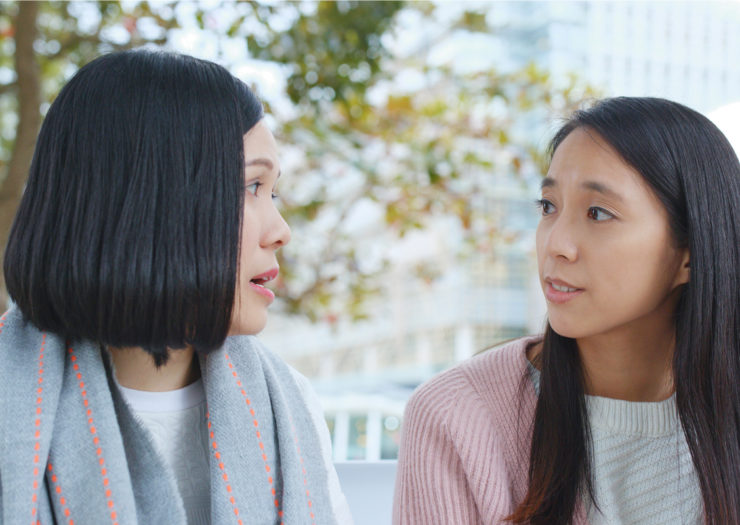 [PHOTO: Two women of Asian descent in conversation outside.]