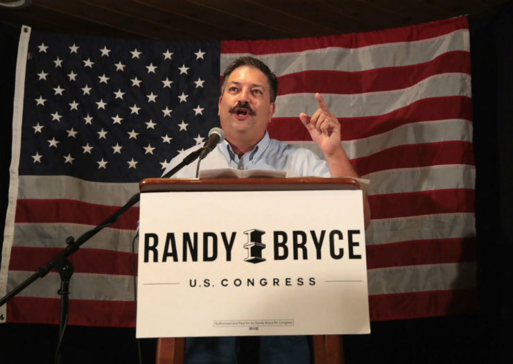 [Photo: Randy Bryce at podium in front of flag.]