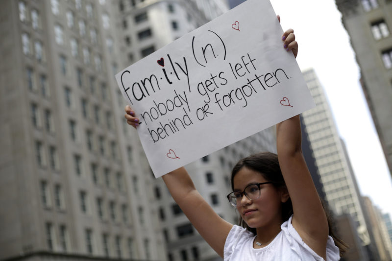 [Photo: A demonstrator protesting against Immigration and Customs Enforcement and the Trump administration's immigration policies holds a sign that reads,