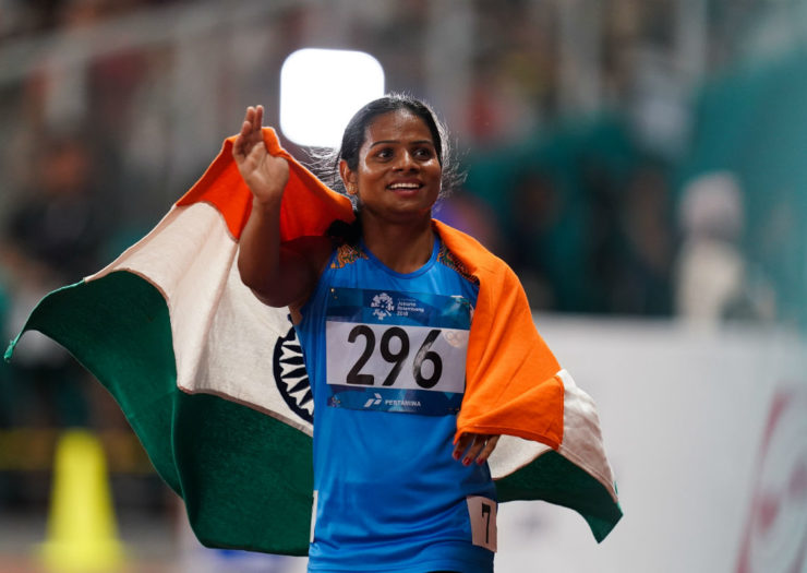 [Photo: Athlete Dutee Chand stands at her podium draped in the Indian flag]