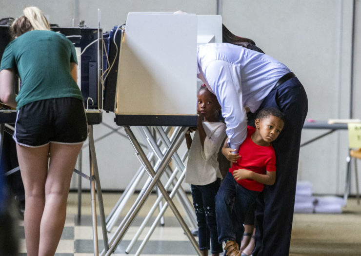 [Photo: Andrew Gillum votes with his two children in tow]