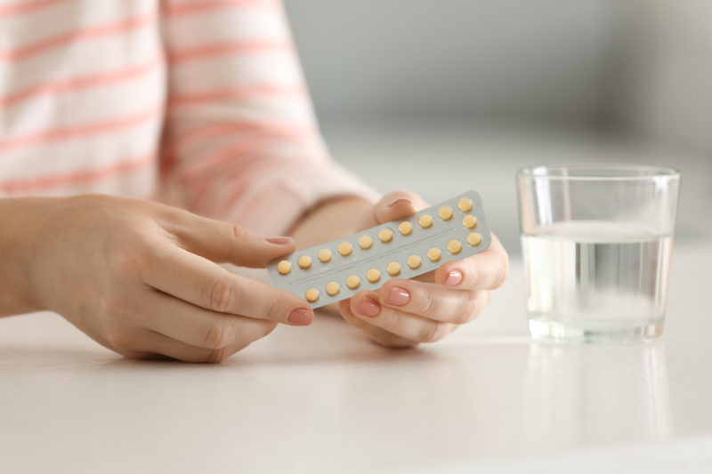 [Photo: Hands holding a pack of birth control pills.]