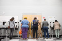 [Photo: Five women of color voting at early voting polls.]
