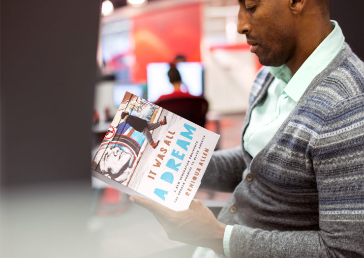 [Photo: Young black man reading a book entitled 'It Was All A Dream.']